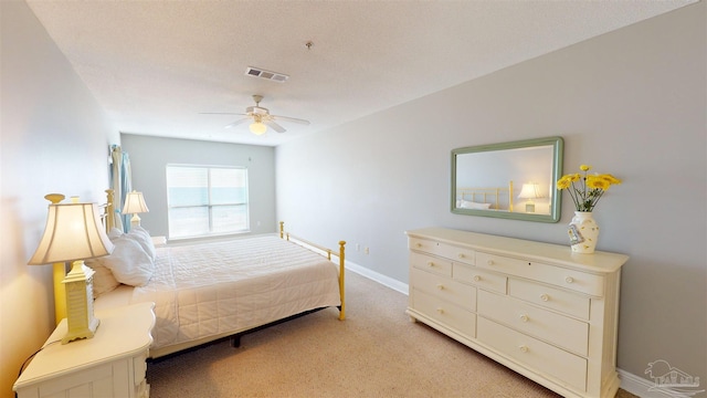 bedroom with ceiling fan, a textured ceiling, and light colored carpet