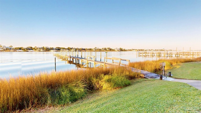 dock area with a lawn and a water view