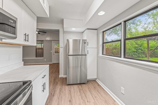 4905 State St, Pensacola, FL 32506 - kitchen featuring stainless steel appliances, light wood-style flooring, white cabinets, light countertops, and healthy amount of natural light