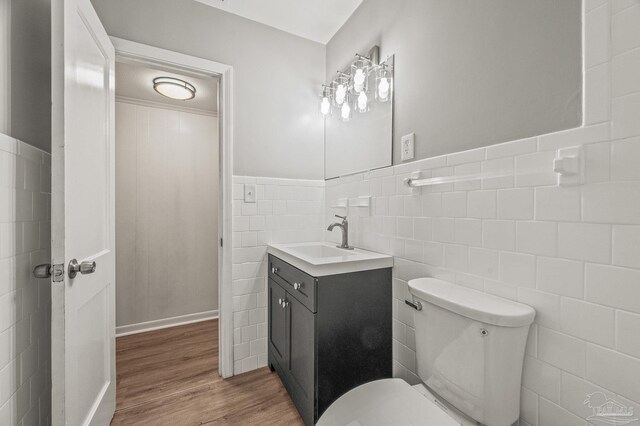 4905 State St, Pensacola, FL 32506 - bathroom featuring tile walls, wood finished floors, toilet, vanity, and a wainscoted wall