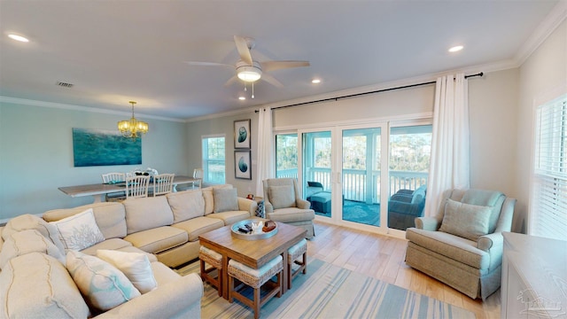 living room with a wealth of natural light, ornamental molding, ceiling fan with notable chandelier, and light wood-type flooring