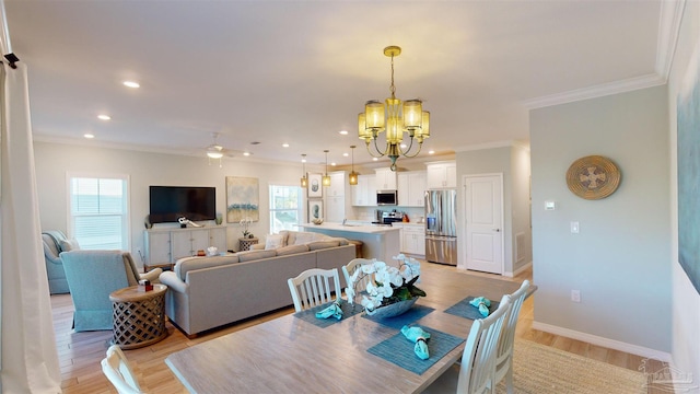 dining space with ornamental molding, ceiling fan with notable chandelier, light hardwood / wood-style floors, and a healthy amount of sunlight