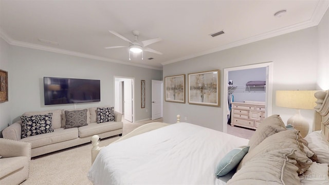 bedroom featuring a walk in closet, a closet, crown molding, and ceiling fan