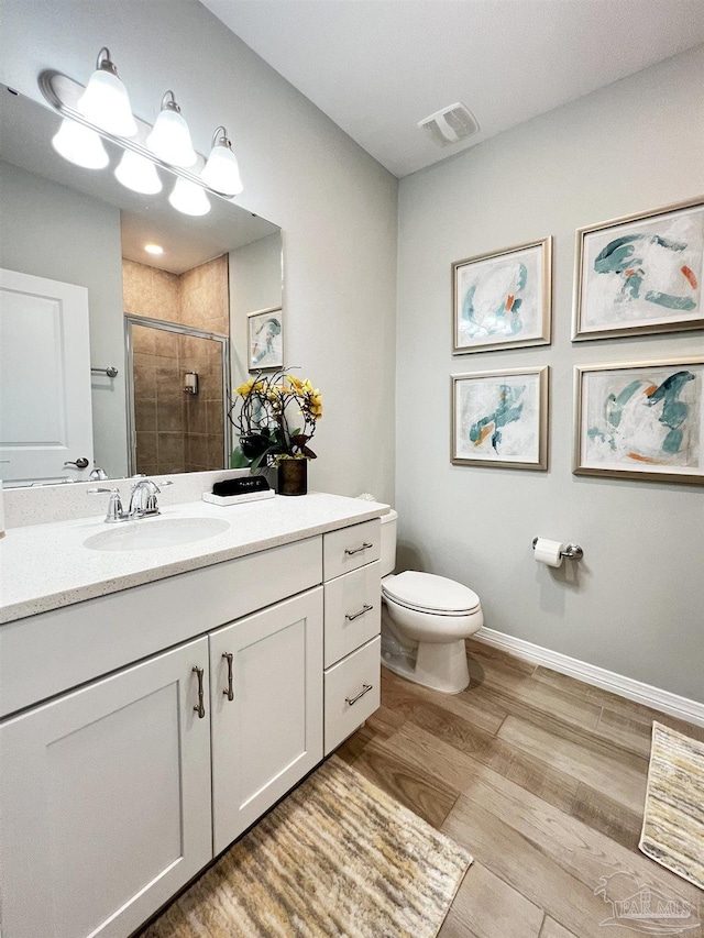 bathroom with toilet, vanity, wood-type flooring, and walk in shower