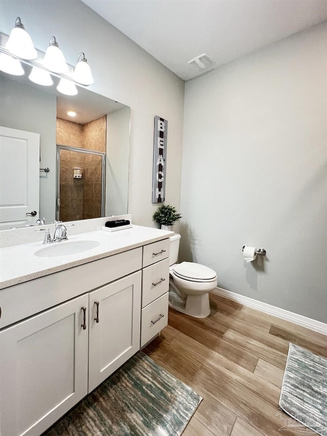 bathroom featuring hardwood / wood-style floors, vanity, toilet, and an enclosed shower