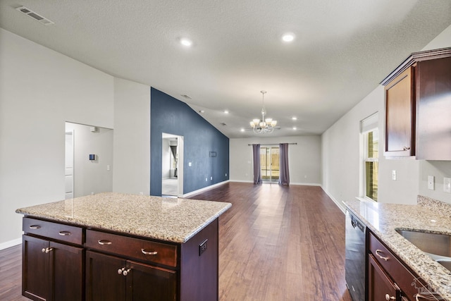 kitchen with dark wood-type flooring, light stone countertops, vaulted ceiling, and a kitchen island