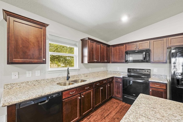 kitchen featuring dark wood-type flooring, lofted ceiling, sink, a textured ceiling, and black appliances