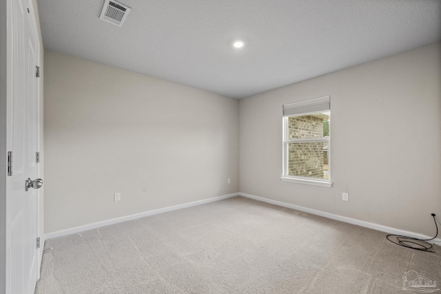 unfurnished room featuring light carpet and a textured ceiling