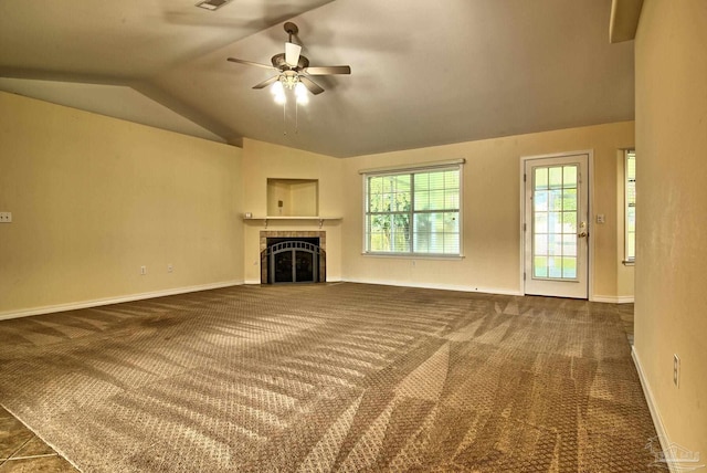 unfurnished living room with a tile fireplace, baseboards, lofted ceiling, and dark colored carpet