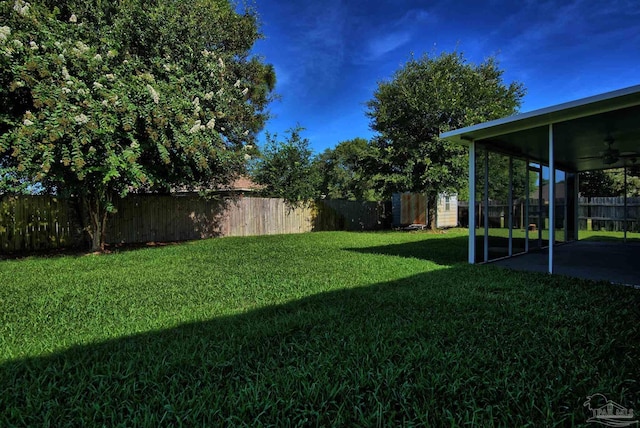 view of yard with an outbuilding, a storage unit, a ceiling fan, a patio area, and a fenced backyard