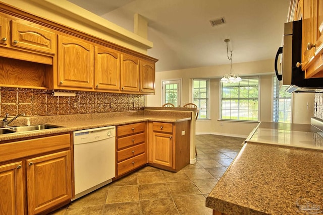 kitchen featuring visible vents, decorative backsplash, brown cabinets, decorative light fixtures, and white dishwasher