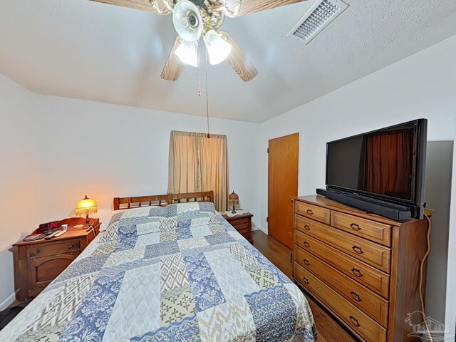 bedroom with ceiling fan, hardwood / wood-style floors, and a textured ceiling