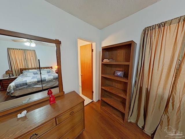 bedroom with hardwood / wood-style flooring, ceiling fan, and a textured ceiling