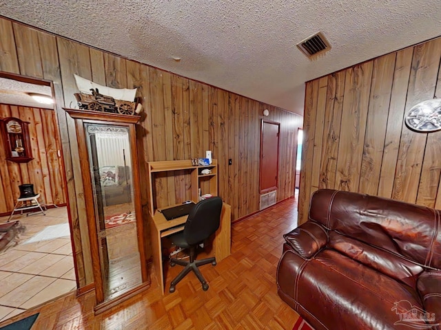 office space with wooden walls, light parquet flooring, and a textured ceiling