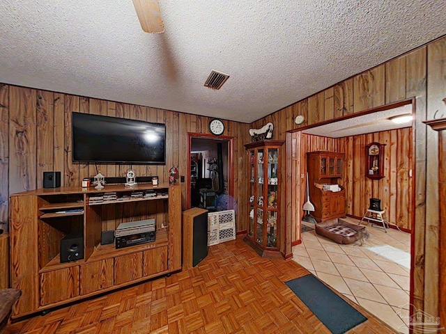 living room featuring a textured ceiling, light parquet flooring, and wood walls