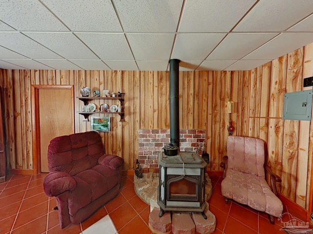 living area featuring tile patterned floors, wood walls, and a wood stove