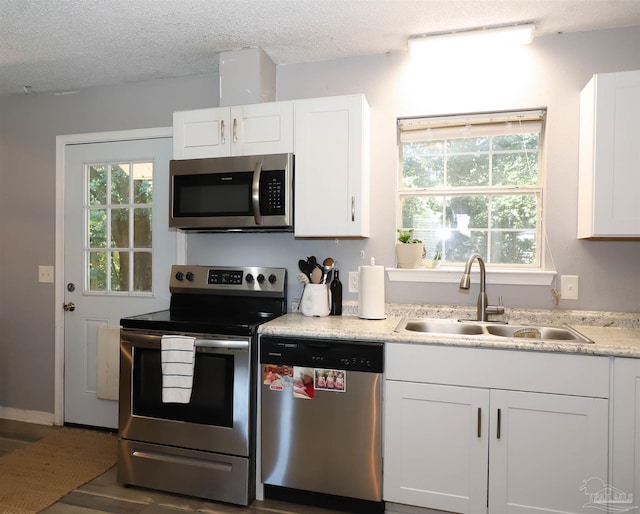 kitchen with a textured ceiling, stainless steel appliances, dark wood-type flooring, sink, and white cabinetry