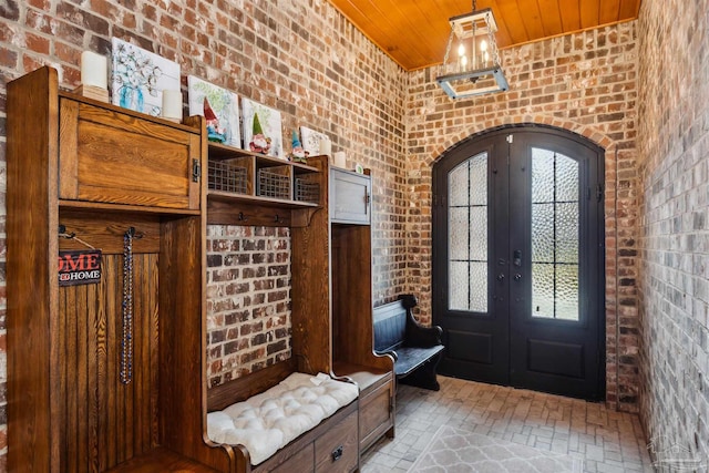 mudroom with brick wall, french doors, and wooden ceiling