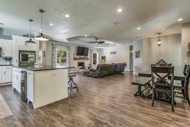 2685 Segrest Rd, Pace, FL 32571 - kitchen featuring a textured ceiling, dark countertops, a fireplace, white cabinetry, and a ceiling fan