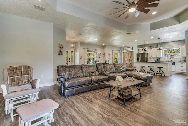 living room with hardwood / wood-style flooring, ceiling fan, and a textured ceiling