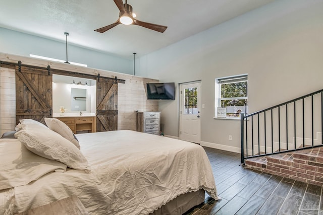 bedroom featuring a high ceiling, a barn door, ceiling fan, and dark wood-type flooring