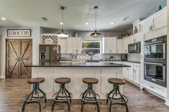 kitchen with a center island, dark hardwood / wood-style floors, decorative light fixtures, white cabinets, and appliances with stainless steel finishes