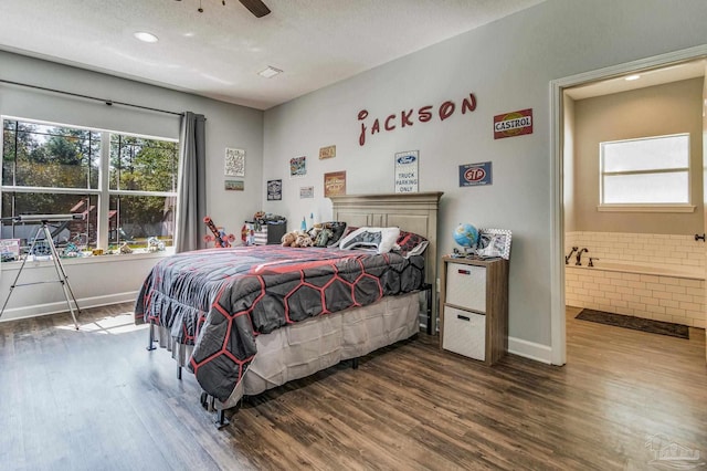 bedroom featuring ceiling fan, dark hardwood / wood-style flooring, ensuite bathroom, and tile walls