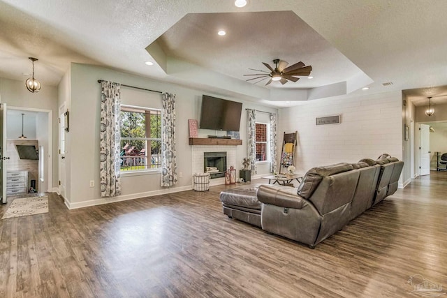 2685 Segrest Rd, Pace, FL 32571 - living room featuring a tray ceiling, wood finished floors, ceiling fan, baseboards, and a brick fireplace