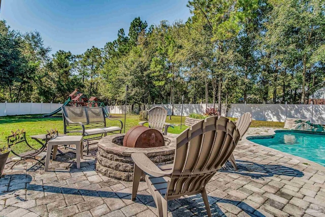 view of patio with a fenced in pool, a playground, and an outdoor fire pit