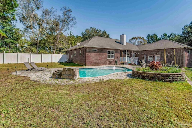 view of pool with pool water feature and a lawn