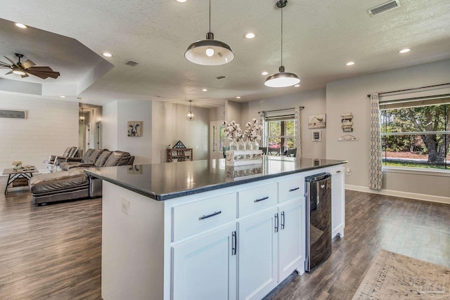 kitchen with a center island, white cabinets, hanging light fixtures, ceiling fan, and a textured ceiling