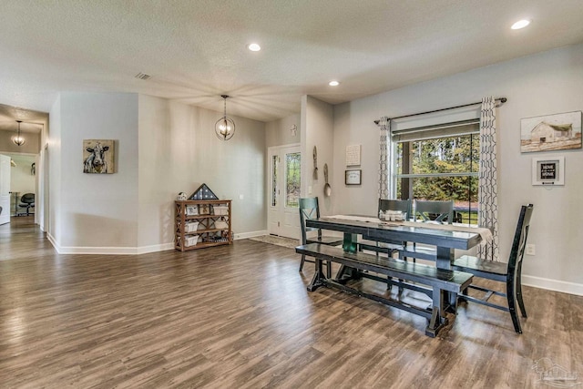 dining area with a textured ceiling, dark hardwood / wood-style floors, and a notable chandelier