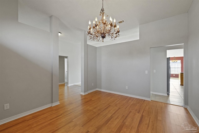 unfurnished room with light hardwood / wood-style floors and a notable chandelier