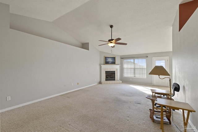 unfurnished room with a tiled fireplace, ceiling fan, carpet floors, and lofted ceiling