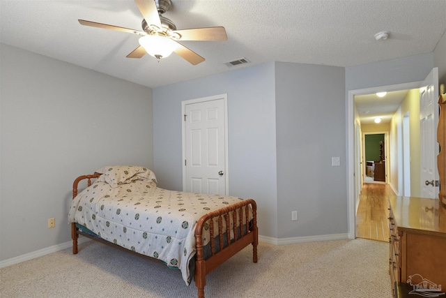 carpeted bedroom featuring ceiling fan and a textured ceiling