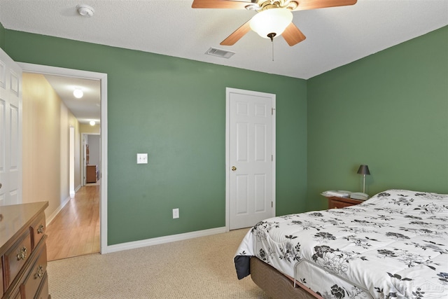 carpeted bedroom featuring ceiling fan and a textured ceiling