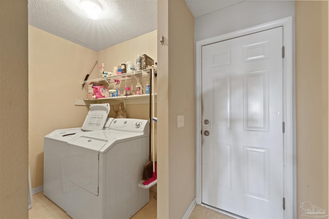 clothes washing area featuring light tile patterned floors, a textured ceiling, and washer and clothes dryer