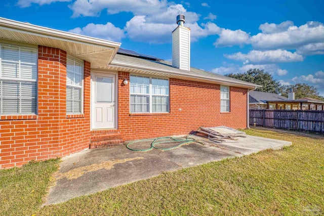 back of property with a lawn, solar panels, and a patio