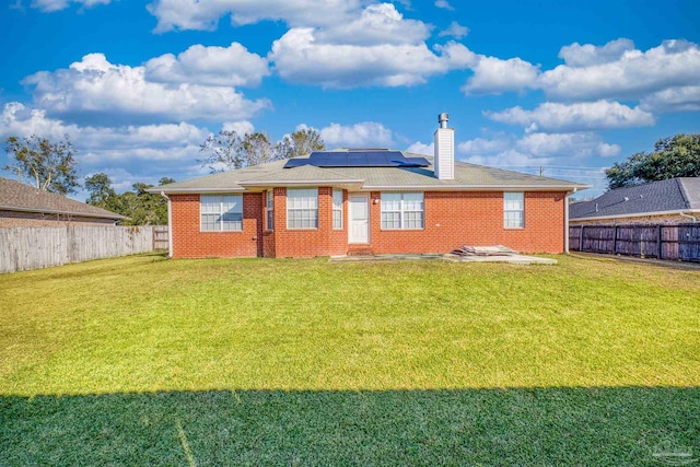 back of property featuring solar panels and a lawn