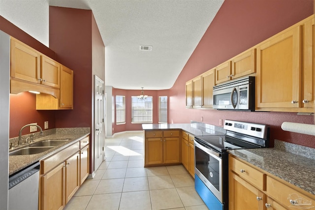 kitchen with sink, stainless steel appliances, a notable chandelier, kitchen peninsula, and light tile patterned floors