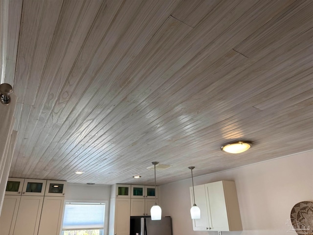 details featuring white cabinets, stainless steel fridge, wooden ceiling, and pendant lighting