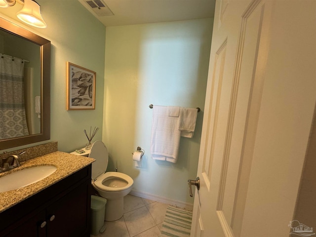 bathroom with toilet, vanity, and tile patterned floors