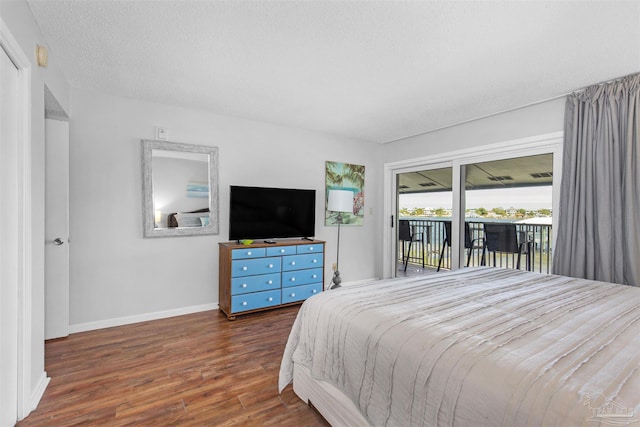 bedroom featuring access to outside, a textured ceiling, and dark hardwood / wood-style flooring