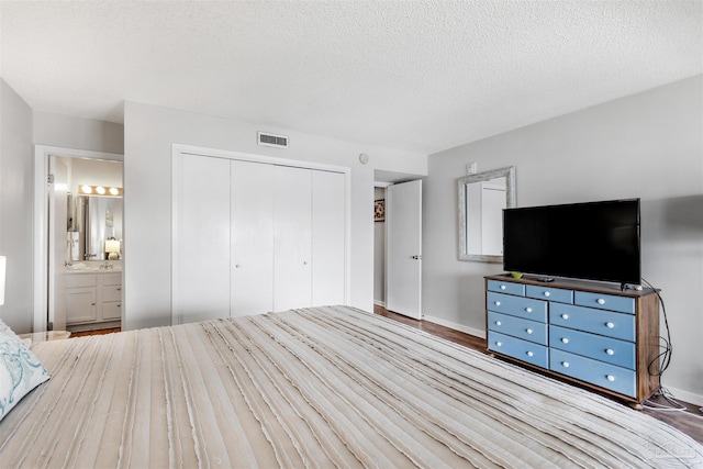 unfurnished bedroom featuring connected bathroom, hardwood / wood-style floors, a closet, and a textured ceiling