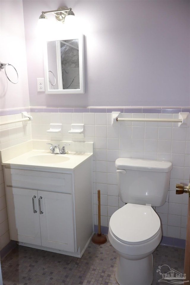 bathroom featuring vanity, tile walls, and toilet