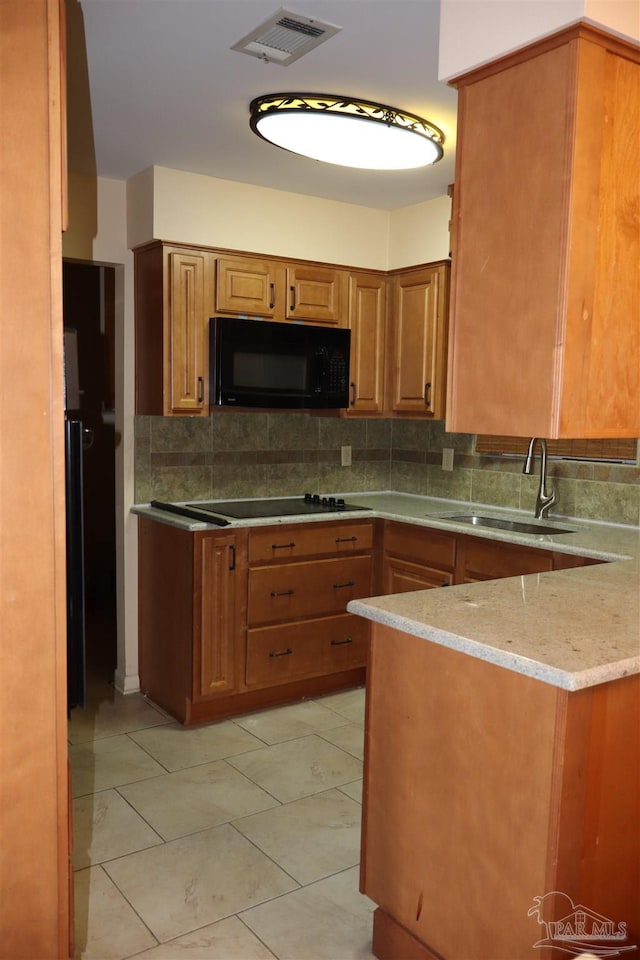 kitchen with sink, light stone counters, black appliances, and backsplash