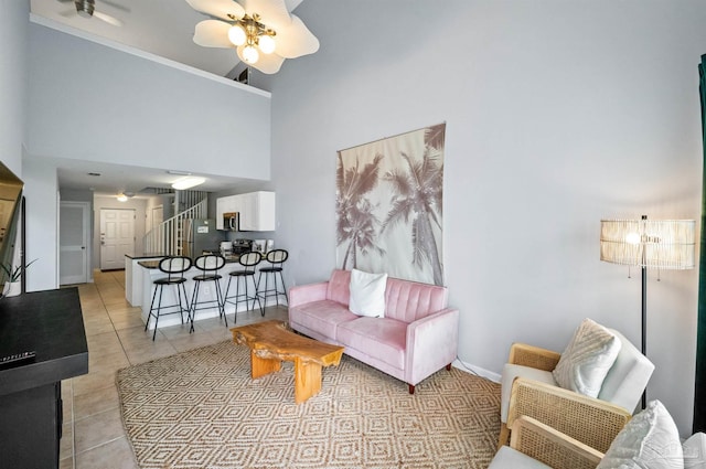 tiled living room with ceiling fan and a high ceiling