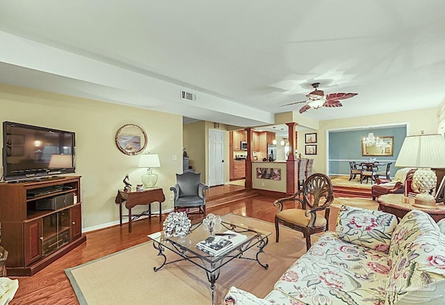 living room with ornate columns, visible vents, a ceiling fan, wood finished floors, and baseboards