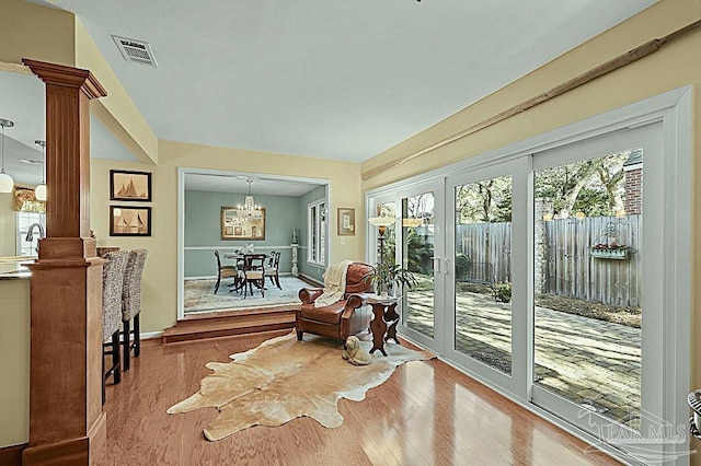 interior space featuring visible vents, wood finished floors, french doors, ornate columns, and a chandelier