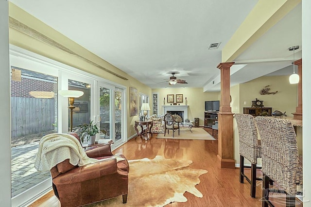 sunroom / solarium with decorative columns, a fireplace, visible vents, and a ceiling fan